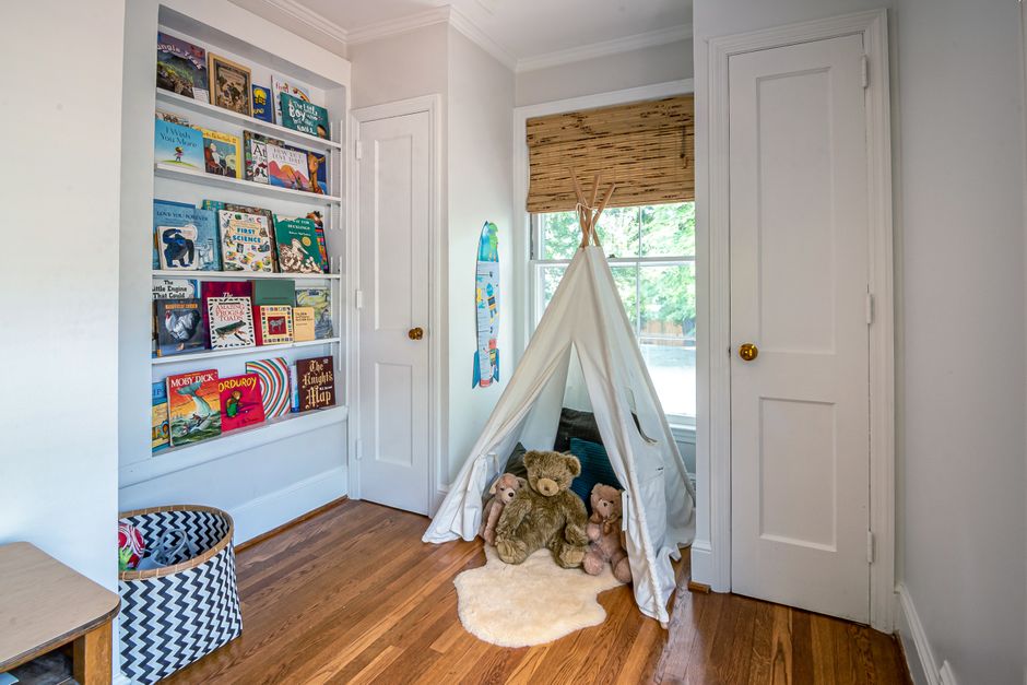 Quarto infantil com livraria, cabana de tecido e pelúcias, ideal para leitura e brincadeiras.