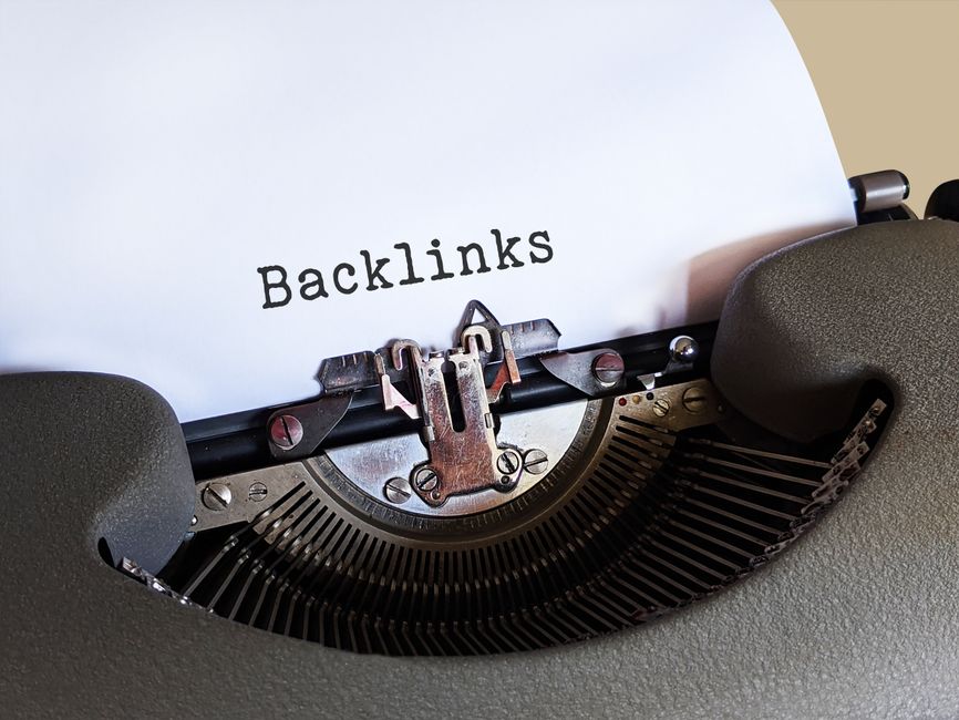 Imagem de uma máquina de escrever com a palavra 'Backlinks' impressa na folha, simbolizando estratégias de marketing digital e SEO.