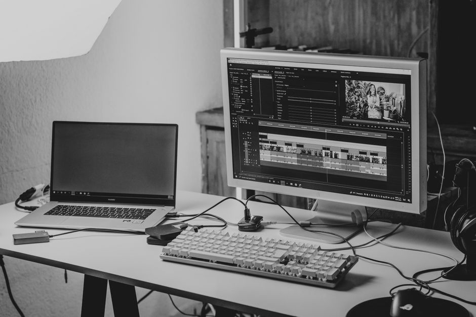 Espaço de trabalho dedicado à edição de vídeos, com computador, monitor grande e equipamentos tecnológicos, ideal para produção de conteúdo audiovisual.