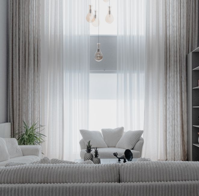 Sala de estar luminosa e moderna com cortinas transparentes, mobiliário aconchegante e decoração minimalista, ideal para ambientes residenciais contemporâneos.