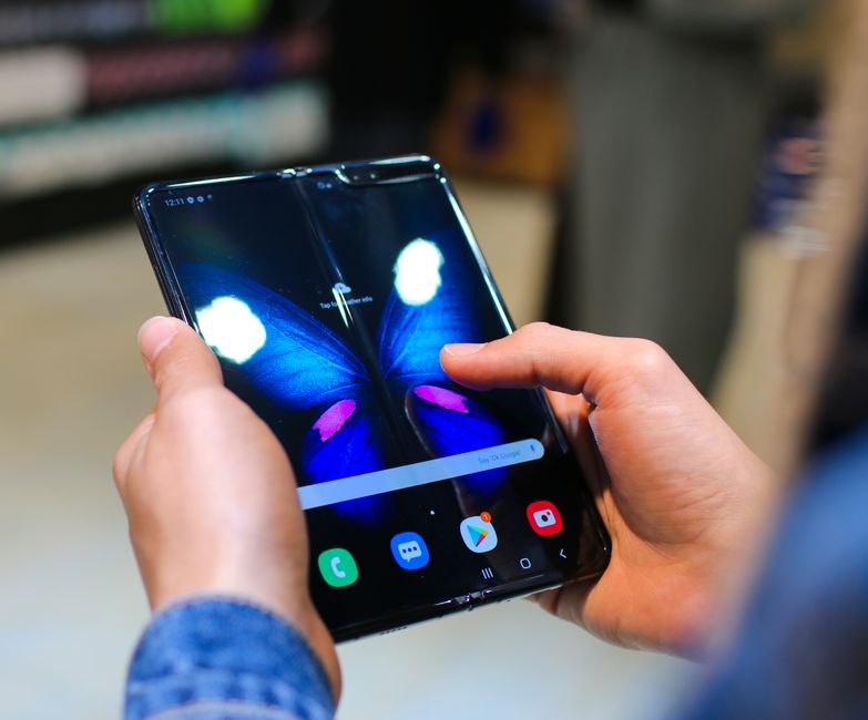 Pessoa usando um smartphone dobrável, destacando tecnologia móvel avançada e inovação.