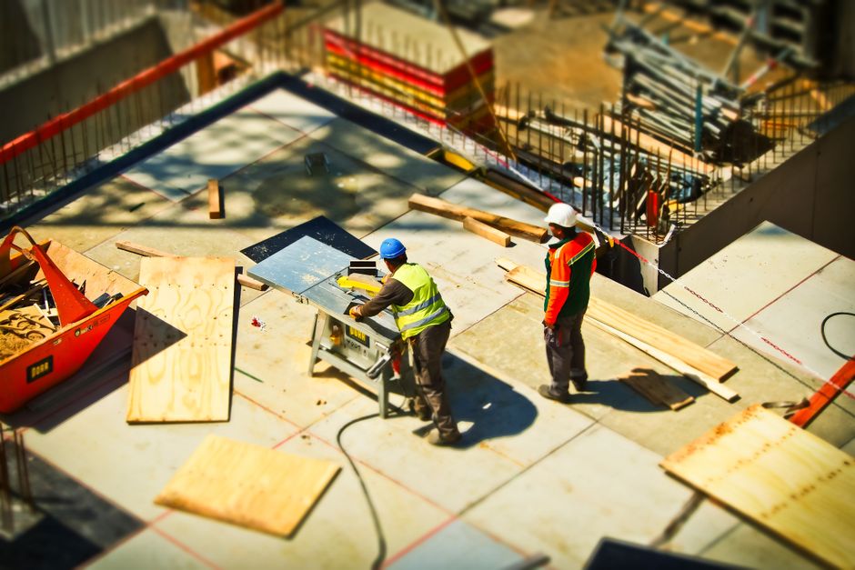 Imagem de uma construção civil com trabalhadores em atividade, simbolizando planejamento e execução de obras.