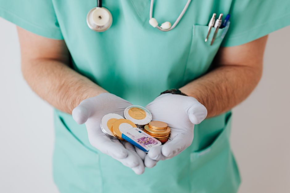 Profissional de saúde segurando moedas e dinheiro em uma abordagem que simboliza custos ou investimentos em saúde.