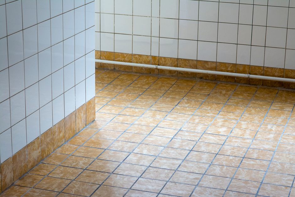Imagem de um ambiente com paredes e piso revestidos de azulejos, comum em banheiros ou cozinhas, com uma orientação para a limpeza e manutenção do espaço.
