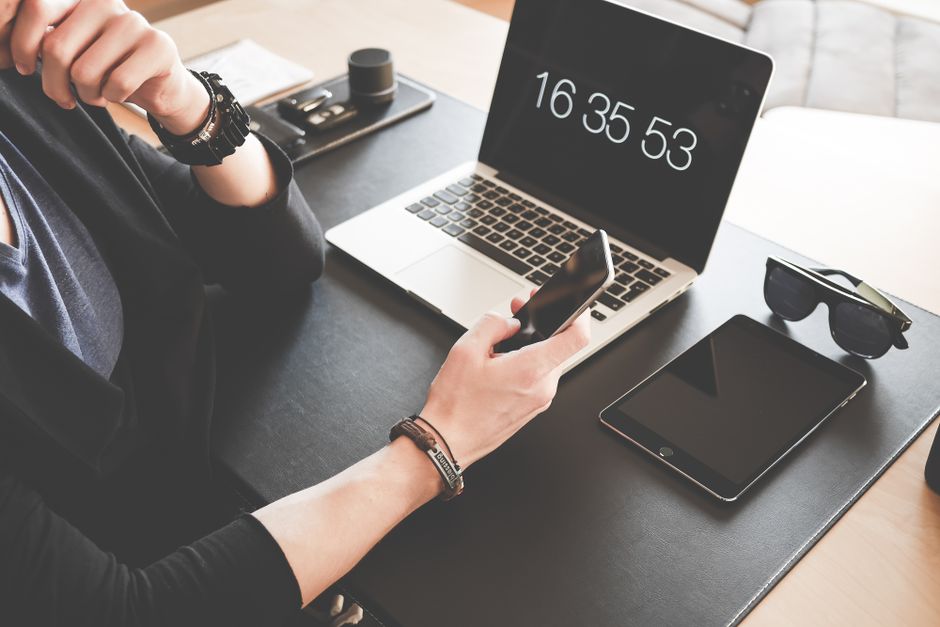 Pessoa utilizando dispositivos móveis e tecnologia para gerenciar tarefas e produtividade no ambiente de trabalho.