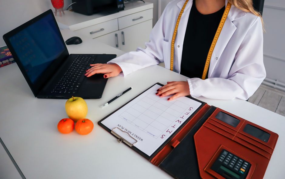Profissional de saúde ou nutricionista preparando registros ou planejamento em um ambiente de escritório.