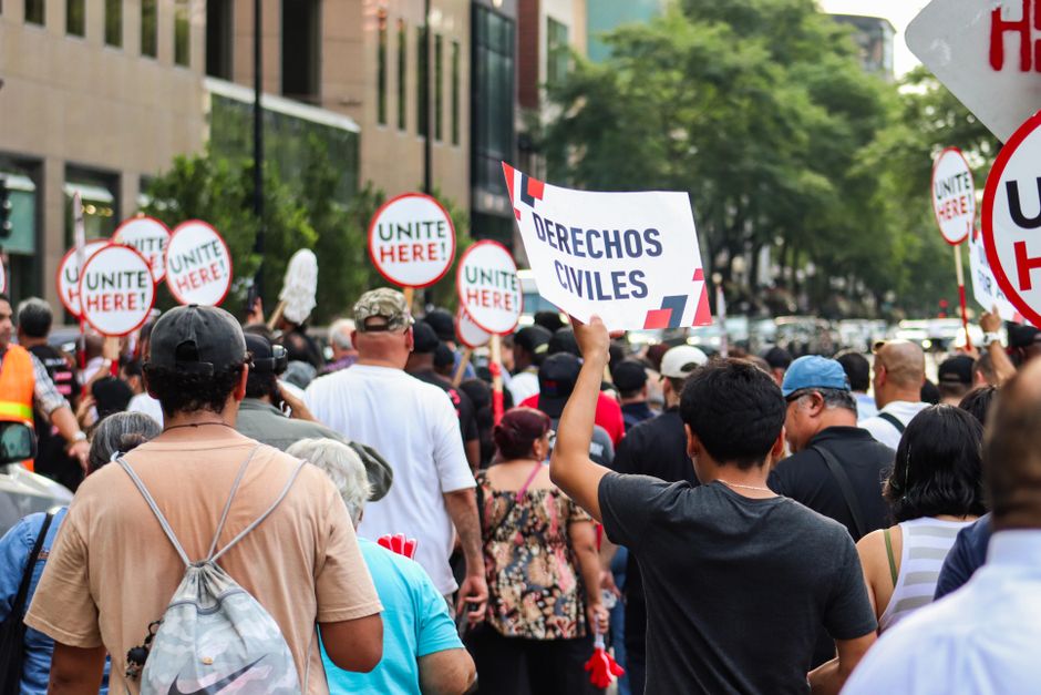 Pessoa segurando cartaz durante protesto por direitos civis em uma rua movimentada da cidade