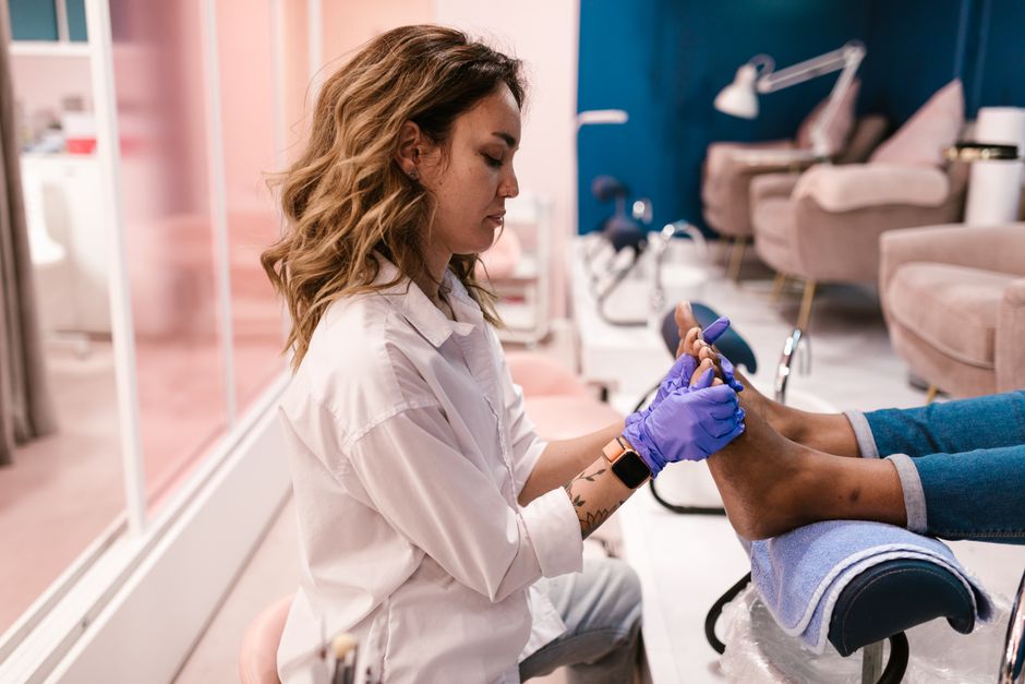 Profissional realizando cuidados de manicure em um ambiente de salão de beleza, focando na atenção e higiene durante o procedimento.