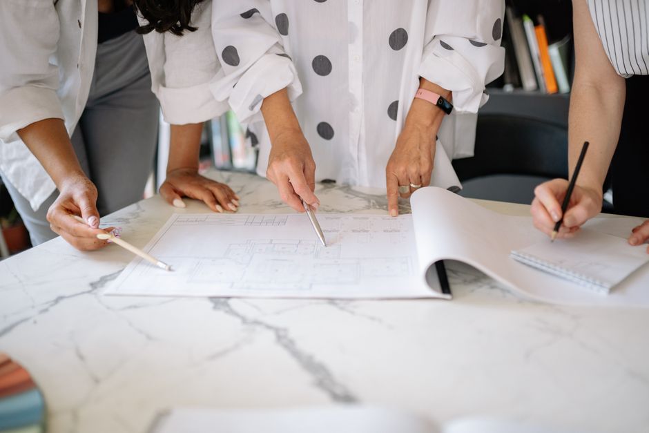 Equipe de profissionais analisando e discutindo um projeto de arquitetura ou planejamento em uma reunião colaborativa.