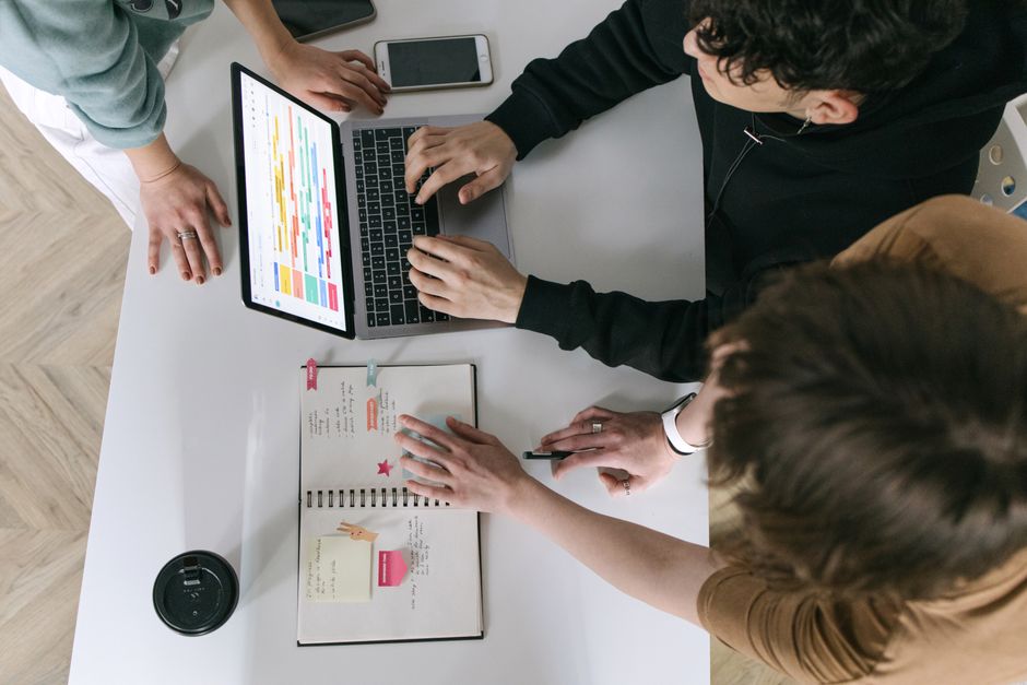 Grupo de pessoas colaborando em planejamento e organização de projetos usando tecnologia e materiais de escritório