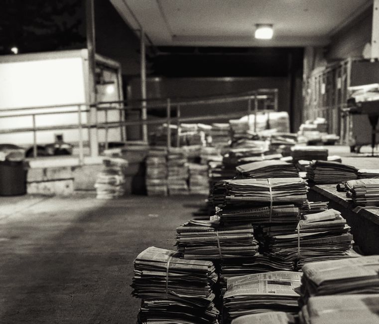 Imagem de pilhas de documentos e papéis empilhados ao ar livre, simbolizando excesso de papelada ou carga de trabalho burocrática.