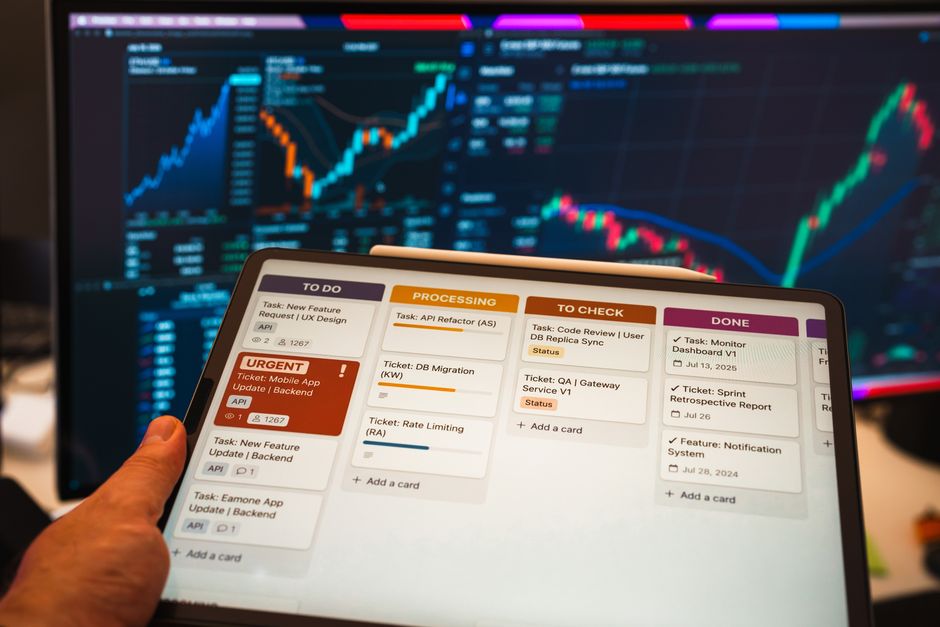 Imagem de um tablet exibindo uma lista de tarefas interativa, com gráficos de mercado financeiros ao fundo, perfeita para ilustrar temas de gestão de projetos e análise de dados financeiros.
