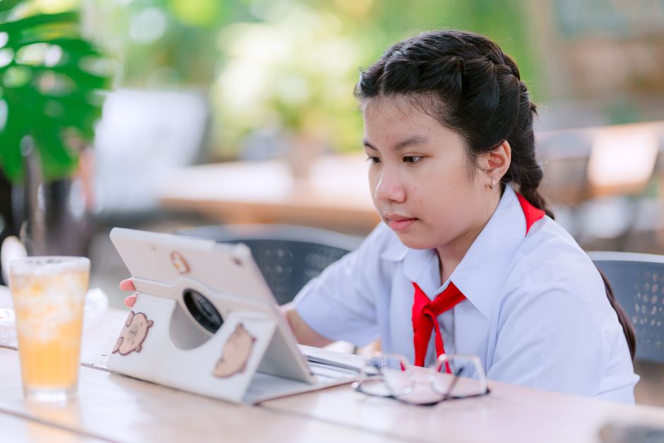 Jovem estudante concentrada usando tablet ao ar livre, representando aprendizado digital e educação moderna.