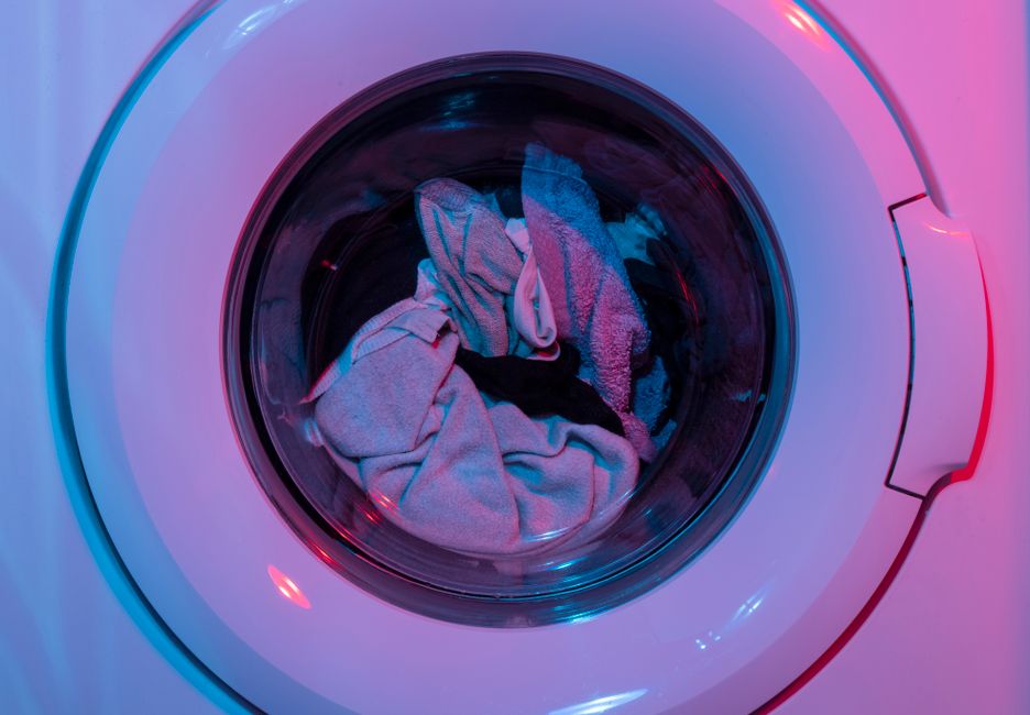 Máquina de lavar roupas em uso, com roupas sujas dentro do acabamento colorido e moderno.