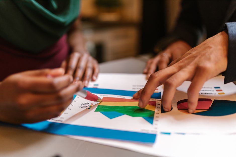 Pessoas analisando gráficos e dados financeiros em uma reunião de negócios ou planejamento estratégico.