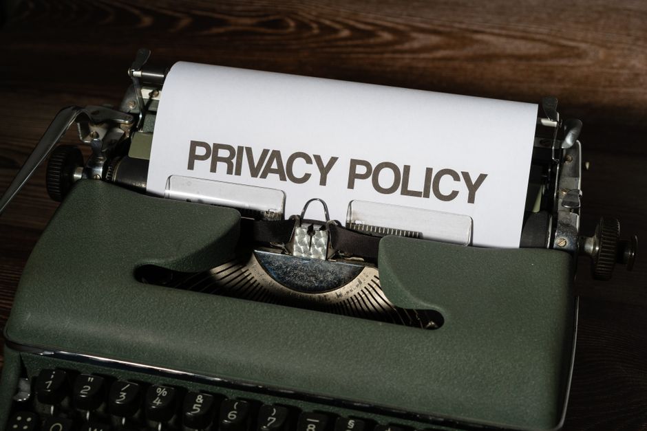 Máquina de escrever com uma folha de papel destacando a frase 'Privacy Policy', representando temas de políticas de privacidade e proteção de dados.