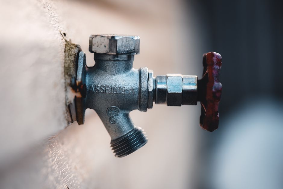 Imagem de uma válvula de água fixada a uma parede, simbolizando controle ou gestão de recursos hídricos.