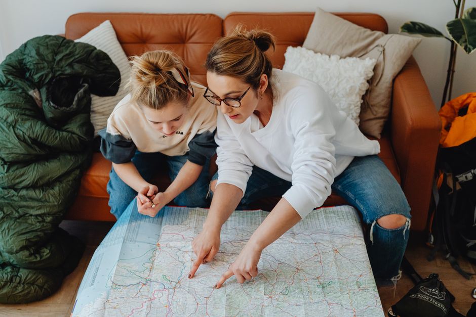 Mulher e criança planejando uma viagem usando um mapa, demonstrando preparação e organização familiar.
