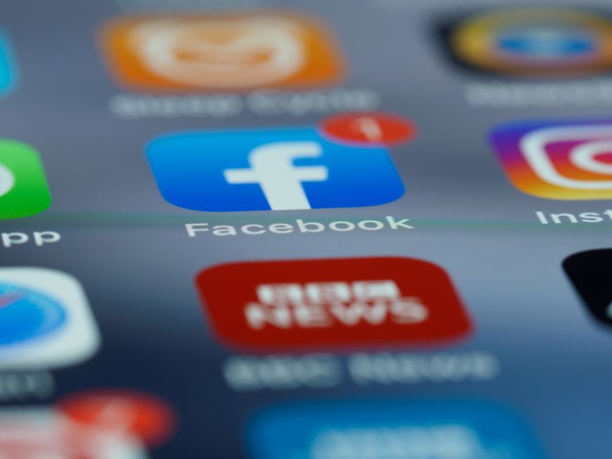 Imagem de tela de smartphone com ícones de redes sociais, destacando o Facebook, relacionada ao tema de comunicação digital e mídias sociais.