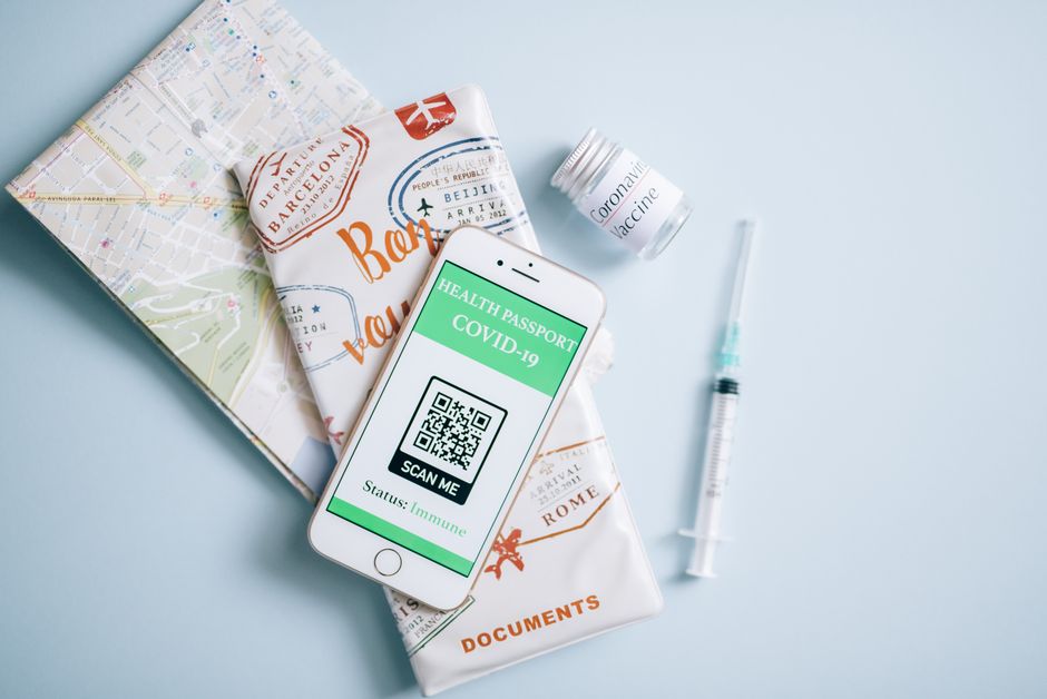 Imagem de itens relacionados à vacinação contra a Covid-19, incluindo vacinas, passaporte de saúde digital e documentos de viagem, sugerindo temas de saúde pública e viagens internacionais.