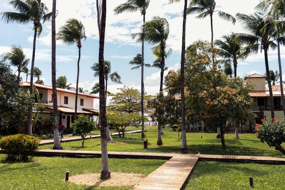 Cenário de resort com casas, palmeiras e ambiente ao ar livre sob céu parcialmente nublado, ideal para destinos de lazer e tranquilidade.