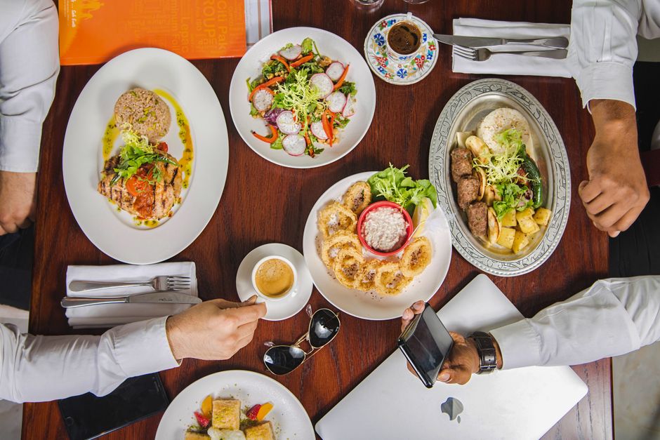 Reunião empresarial com foco em networking e troca de experiências, com refeições sendo compartilhadas à mesa.