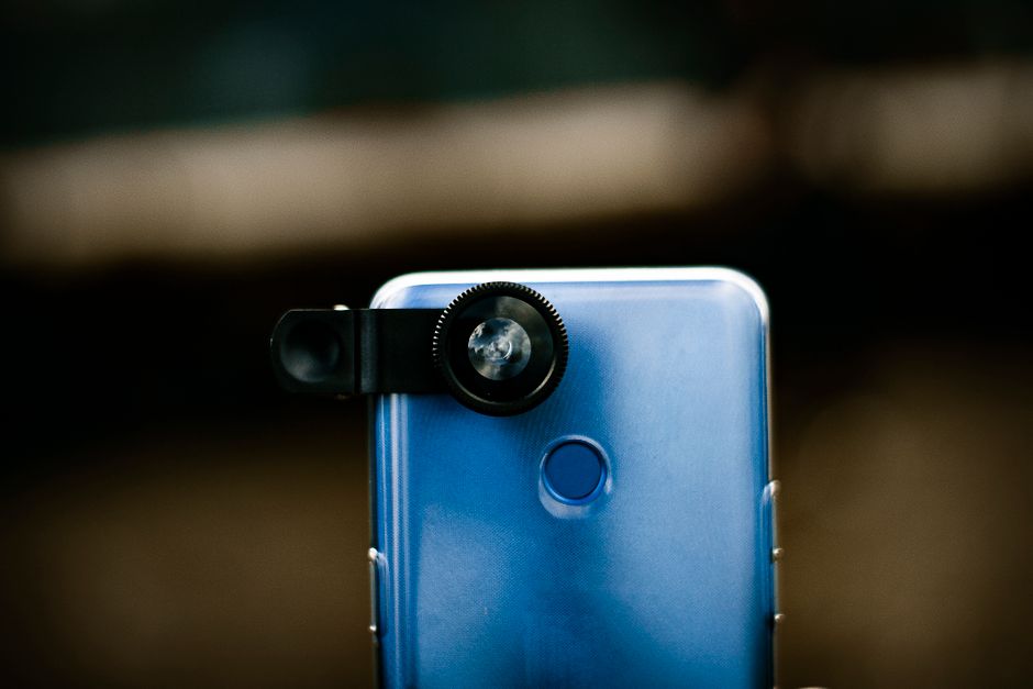 Imagem de um smartphone azul com uma lente adicional acoplada, destacando a tecnologia móvel e fotografia