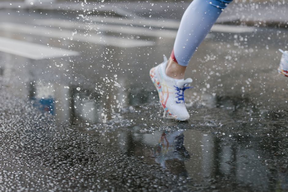 Pessoa em movimento pulando na chuva com tênis esportivos, simbolizando energia e dinamismo.