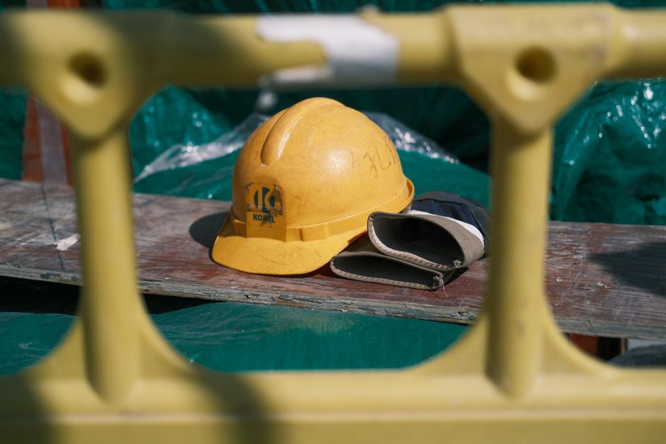 Capacete de segurança e luvas de proteção em um ambiente de construção, simbolizando segurança e trabalho na área da engenharia ou construção civil.