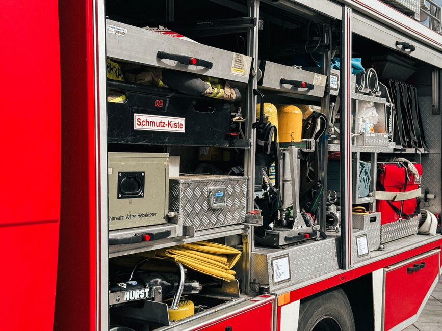 Imagem de uma ambulância com equipamentos de emergência organizados na caixa de armazenamento, simbolizando prontidão e assistência médica.