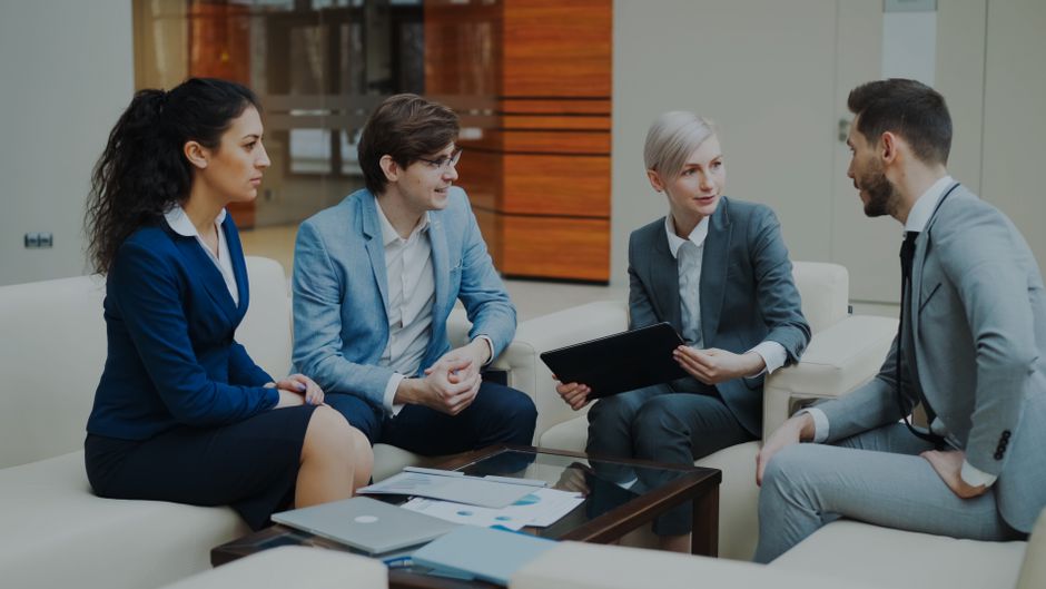 Reunião de equipe discutindo estratégias de negócios em um ambiente profissional formal.