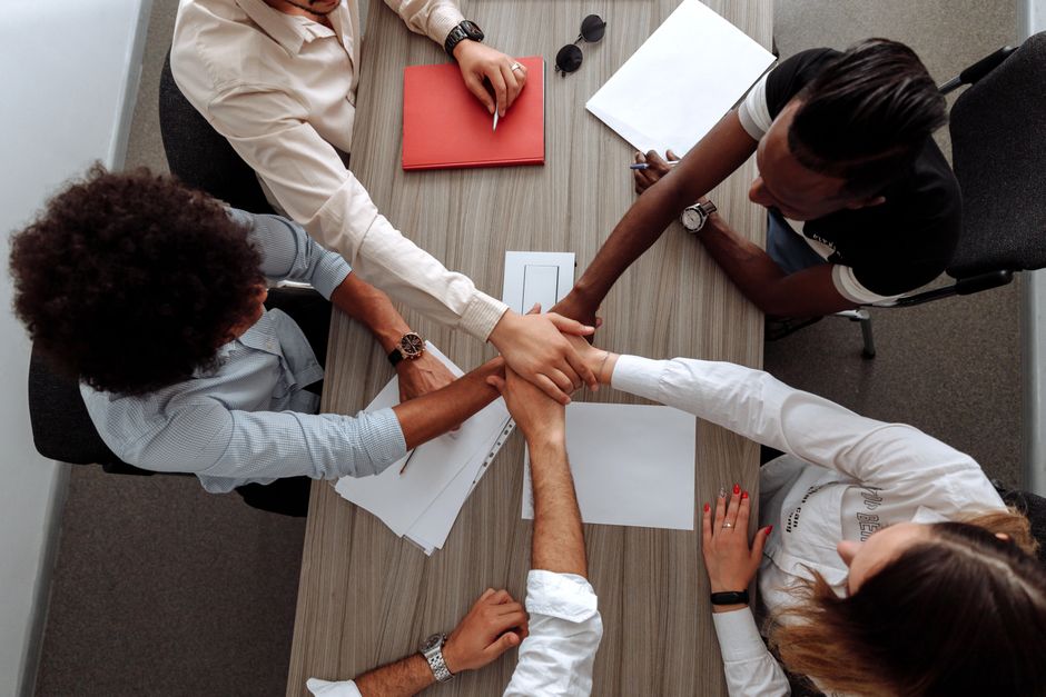 Equipe de profissionais demonstrando cooperação e união em uma reunião de trabalho.