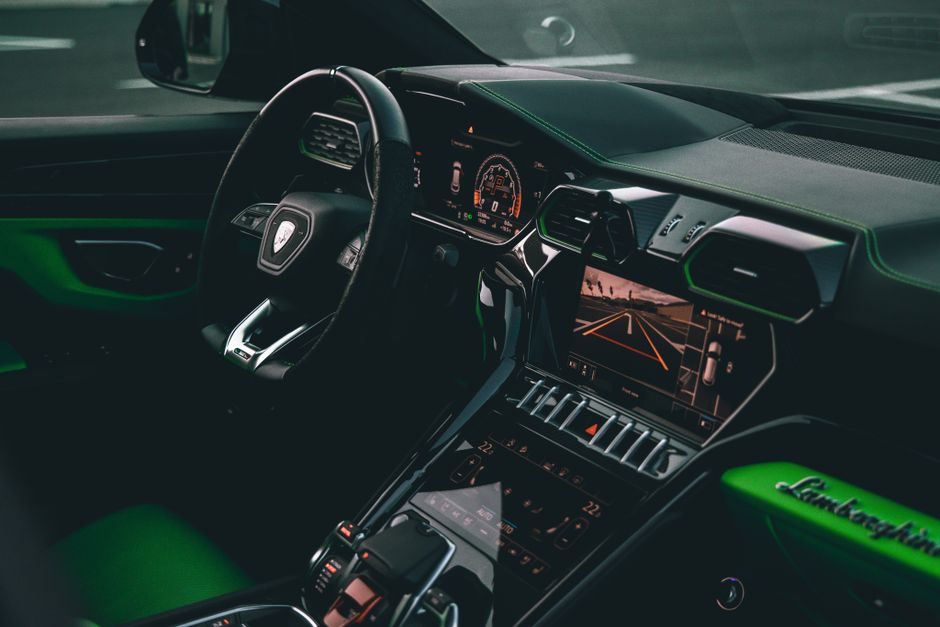 Interior de carro esportivo de luxo com painel digital e assentos esportivos, destacado numa condução urbana moderna.