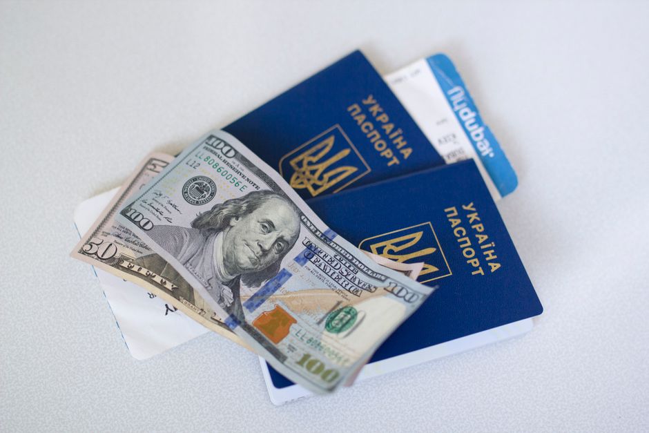 Imagem de passaportes, dinheiro em notas de dólar e cartões de embarque, simbolizando viagem internacional e documentação de viagem.