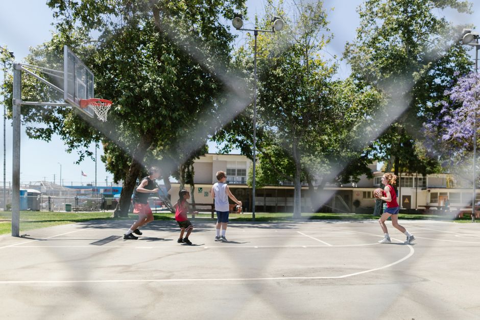 Crianças jogando basquete em uma quadra ao ar livre, transmitindo diversão e esportes infantis em um ambiente de rua.