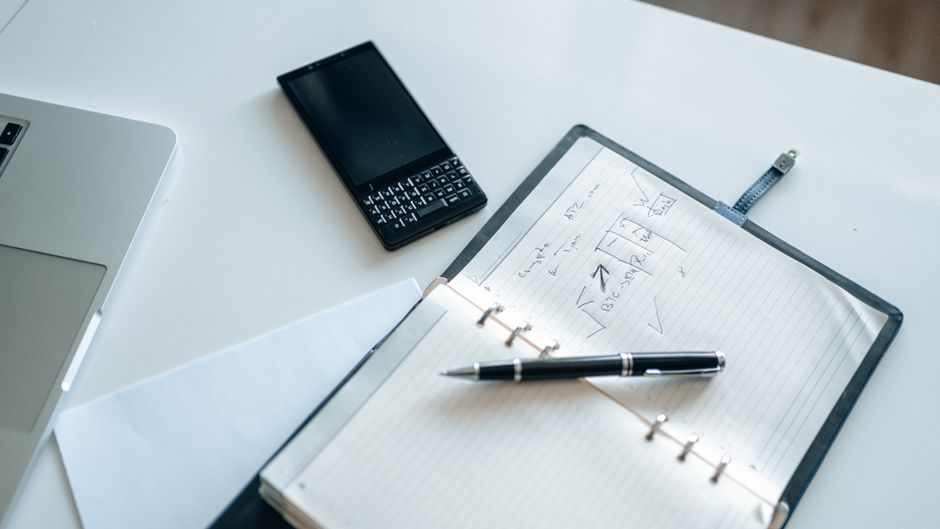 Imagem de uma mesa de trabalho com planilha financeira, notebook, celular e material de escritório, ideal para artigos sobre planejamento financeiro e gestão de negócios.