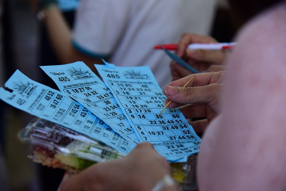 Pessoa segurando bilhetes de loteria enquanto observa opções, representando esperança e jogo de azar.