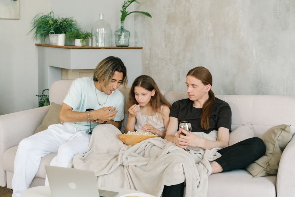 Família assistindo a um filme ou programa juntos no sofá de uma sala de estar moderna e aconchegante.