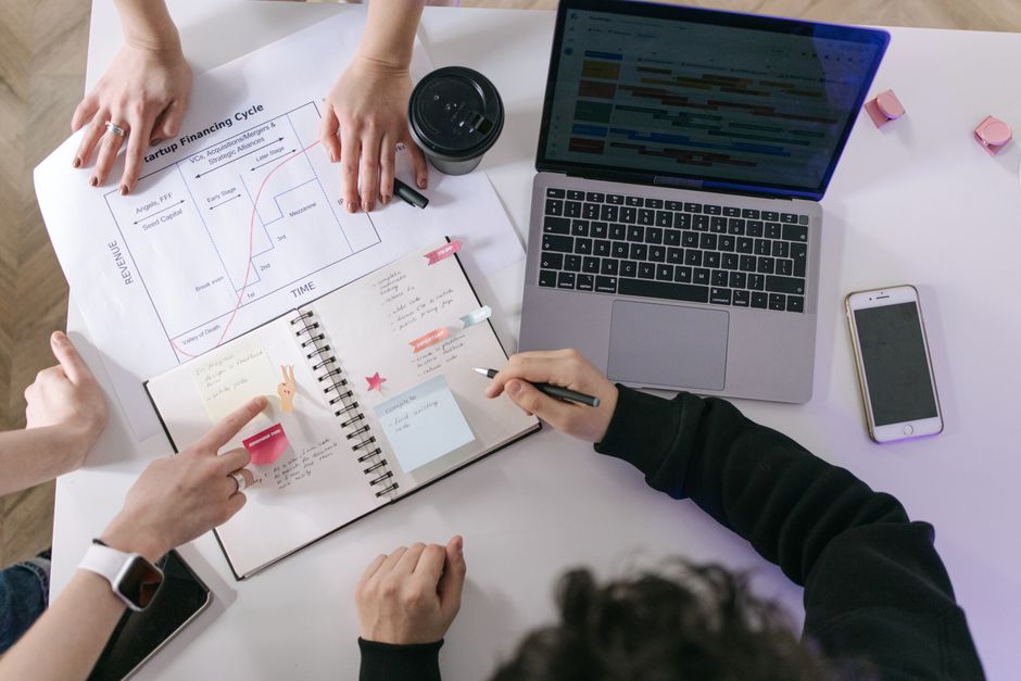 Imagem de uma equipe de trabalho analisando dados financeiros e planejamento estratégico em uma mesa de escritório.