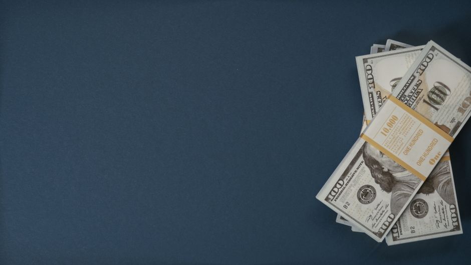 Pacote de cédulas de dinheiro americano sobre fundo escuro, simbolizando temas financeiros e econômicos.
