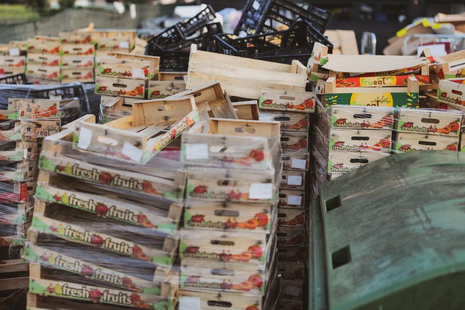 Imagem de caixas de frutas em um ambiente de armazenamento ou transporte, indicando a logística de distribuição de alimentos frescos.