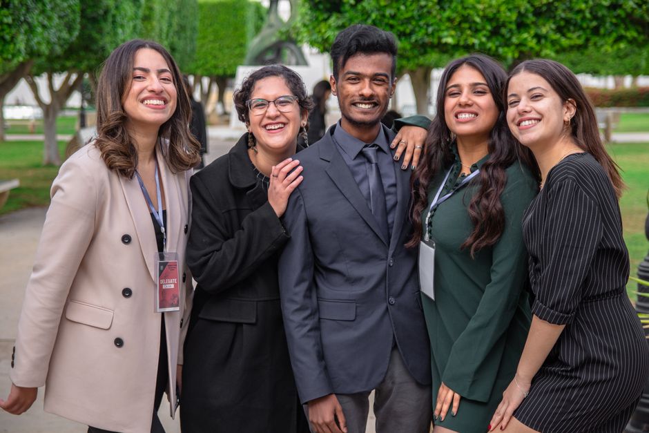 Grupo diverso de pessoas sorrindo ao ar livre, simbolizando inclusão e trabalho em equipe em um ambiente profissional ou acadêmico.