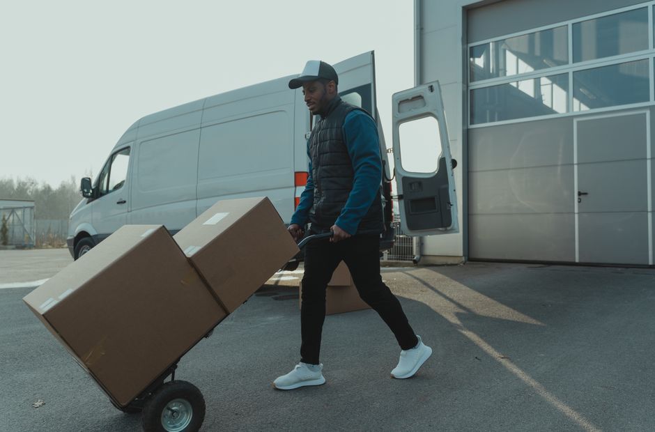 Homem transportando caixas de forma eficiente na área de logística, ilustrando conceitos de gestão de estoque e distribuição.
