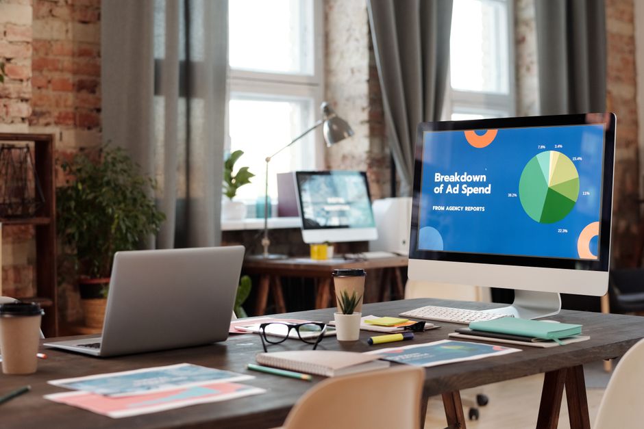 Imagem de um espaço de trabalho moderno com computadores exibindo gráficos e relatórios financeiros, ideal para artigos sobre gestão financeira e análise de dados empresariais.