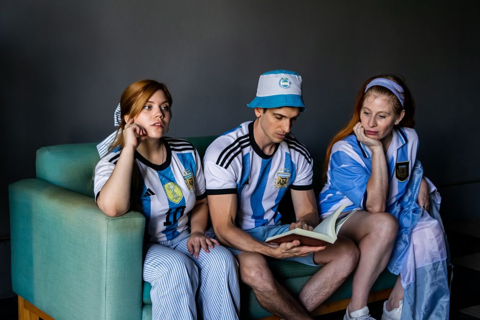 Grupo de pessoas assistindo a uma partida de futebol vestindo camisas da seleção argentina, demonstrando empolgação e torcida.
