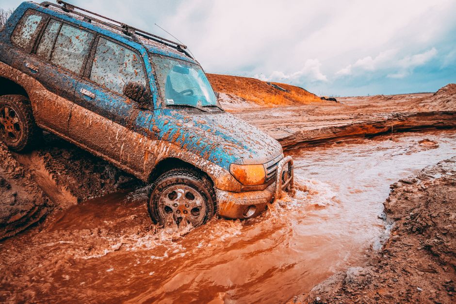 Veículo off-road atolado em uma área de lama ou barro, sugerindo aventura ou desafio em ambientes rurais ou de natureza selvagem.