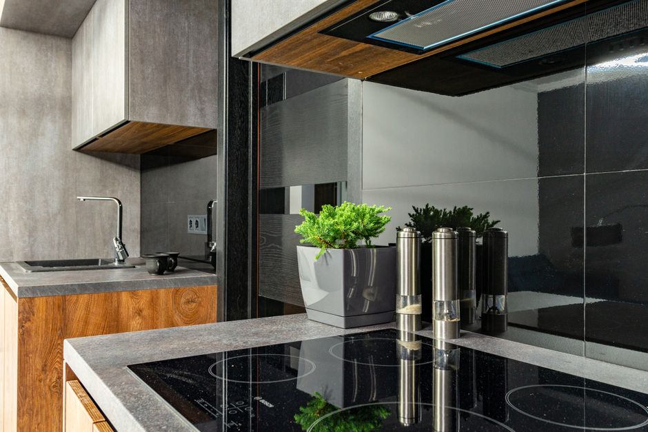 Imagem de uma cozinha moderna com bancada de granito, panelas de vidro e temperos, ideal para artigos sobre organização e design de interiores de cozinhas.