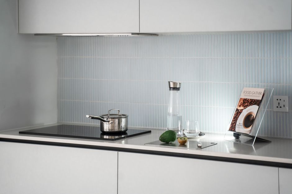 Imagem de uma cozinha moderna com utensílios minimalistas, incluindo panela no fogão, garrafas de água, frutas e uma revista de culinária, ideal para ilustrar dicas de receitas ou organização da cozinha.
