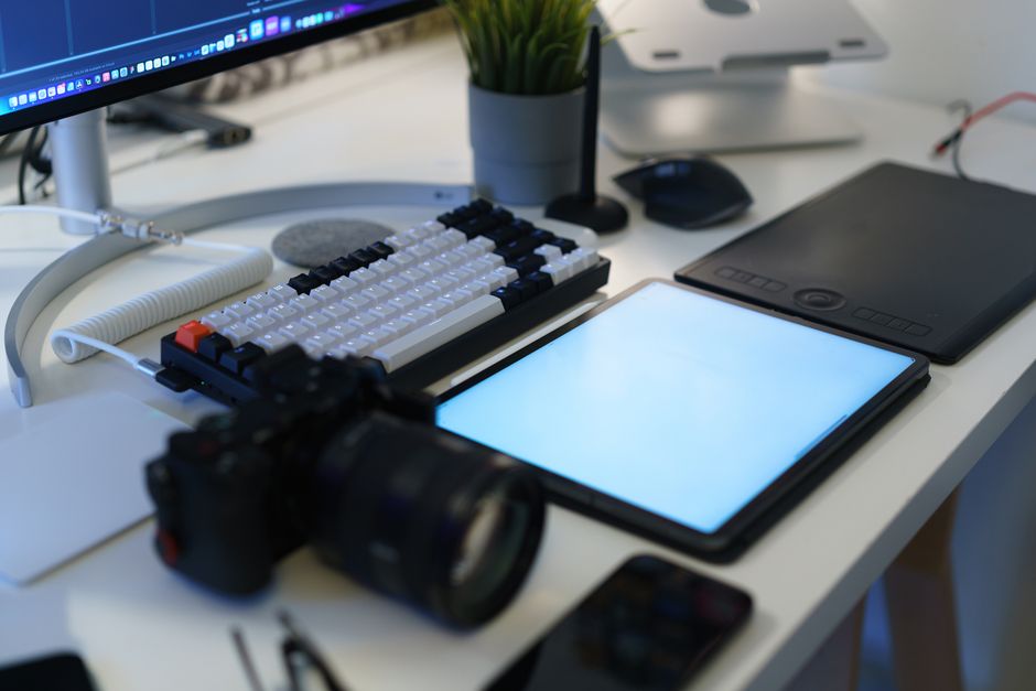 Imagem de uma estação de trabalho moderna com computador, tablet, câmera e mesa digitalizadora, ideal para conteúdo sobre tecnologia, design ou jornalismo digital.