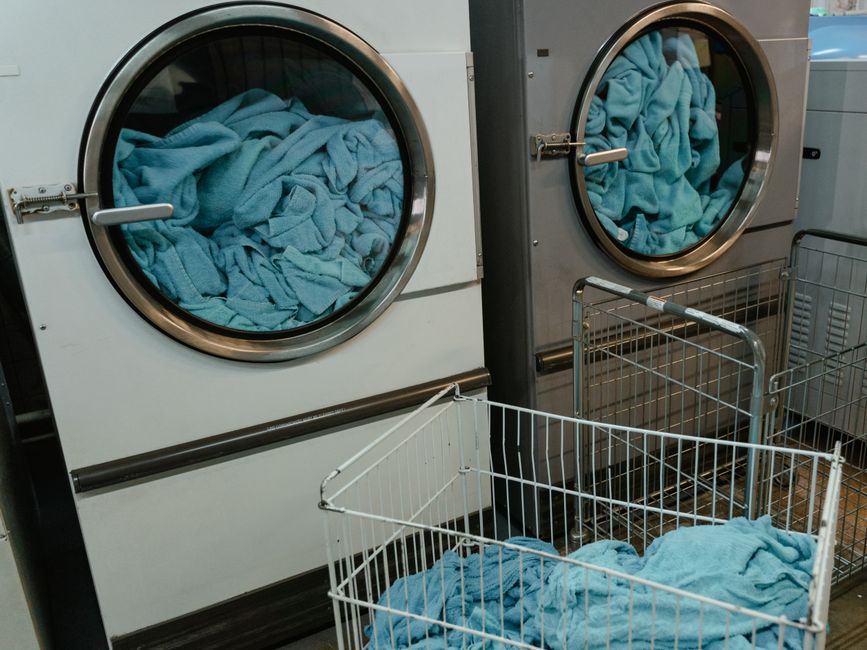 Máquinas de lavar roupas industriais em um ambiente de lavanderia, destacando o processo de lavagem em grande escala.